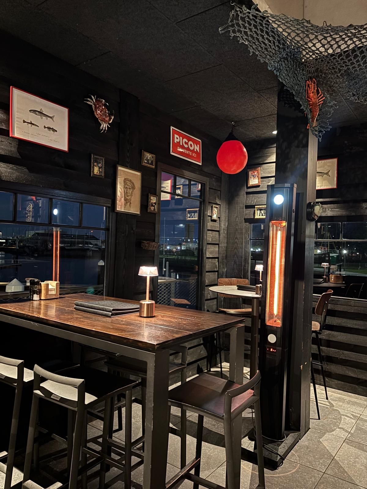 Zithoek tussen zwarte houten wanden en ramen in restaurant 't Werftje in Zeebrugge